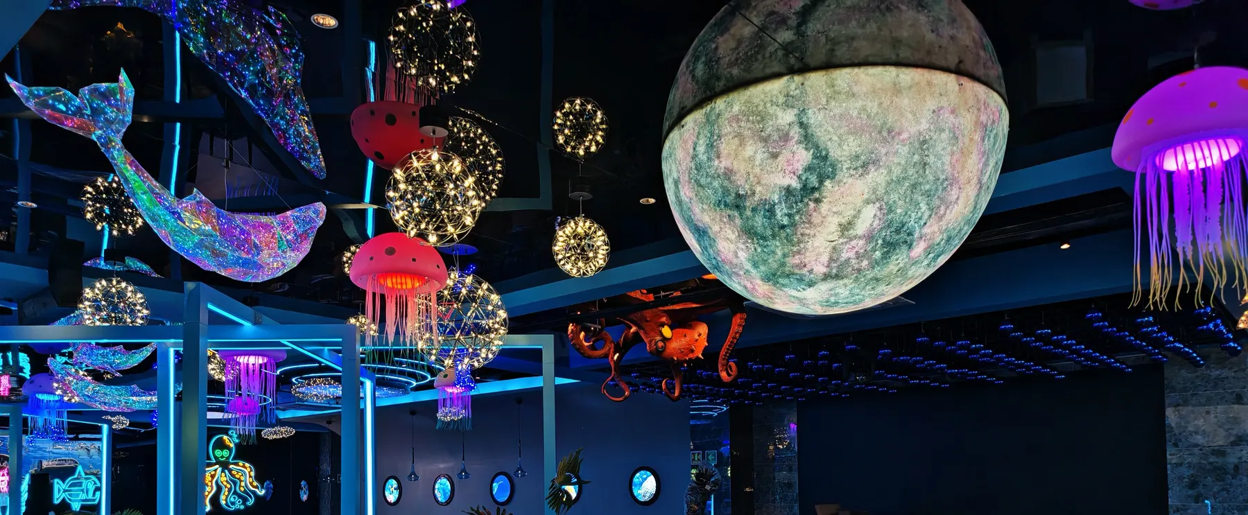 Ballena iridiscente, medusas de colores y una luna colgante sobre el comedor